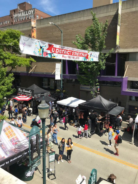 Photo looking down on University Way with a banner stating University District StreetFair